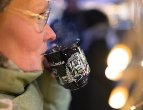 Eine Frau trinkt Glühwein auf dem Helgoländer Weihnachtsmarkt
