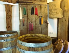 A nostalgic room with old wooden barrels and colorful wax candles on the wall. Notes are attached to a piece of paper.