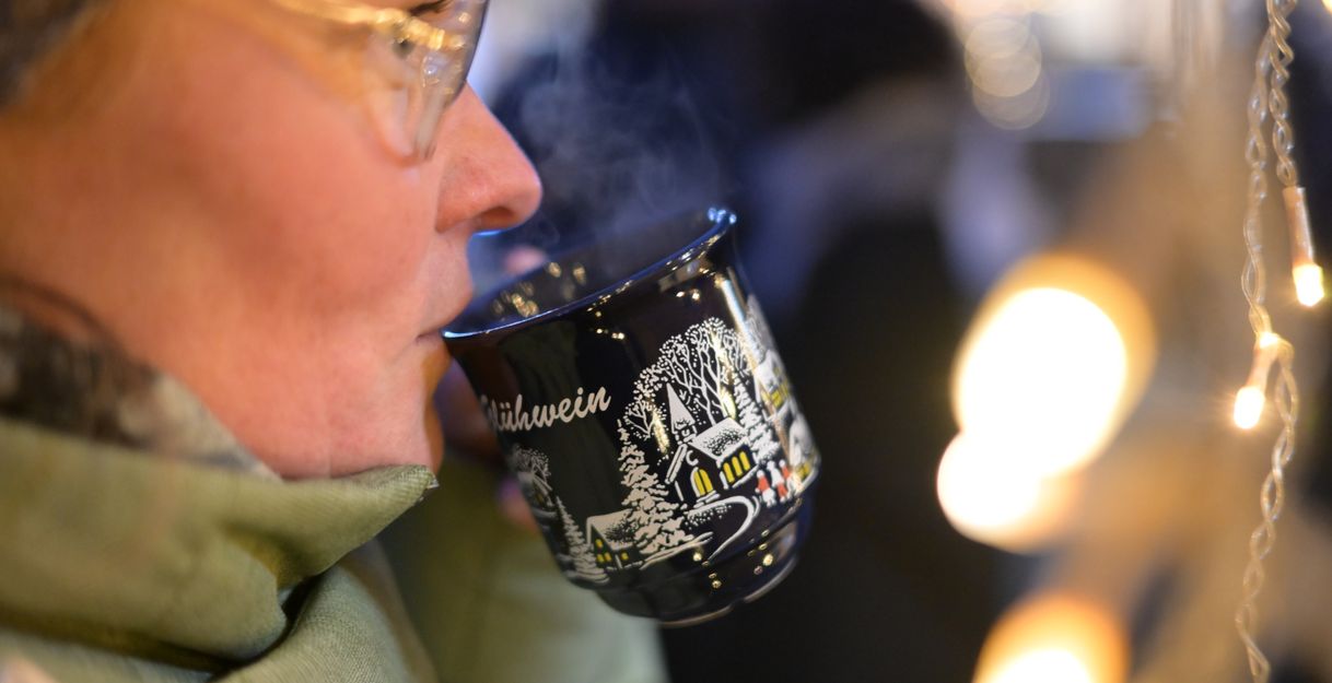 Eine Frau trinkt Glühwein auf dem Helgoländer Weihnachtsmarkt